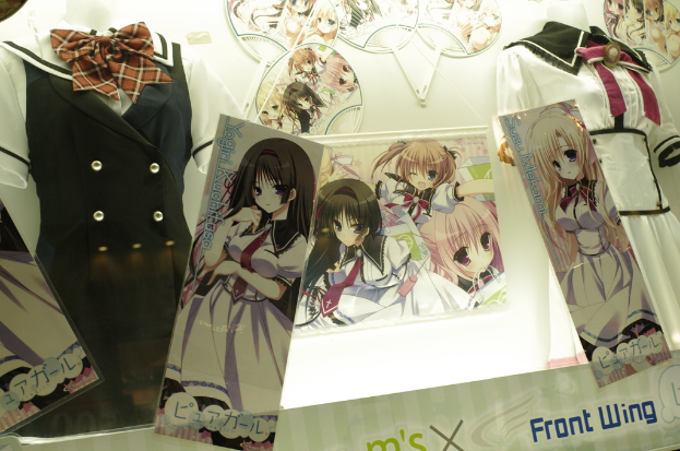 Schaufensterpuppen in verschiedenen Outfits vor einer Wand mit Cartoon-Bildern.