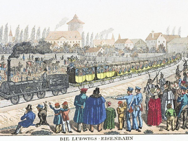 Gruppe von Menschen um einen Zug auf Schienen versammelt, mit einigen im Zug sitzend und anderen draußen stehend, mit Gebäuden und Bäumen im Hintergrund und Text 'Ludwigs-Eisenbahn, der erste Bahnhof in Deutschland' unten.