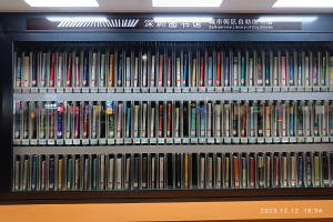 Eine gut beleuchtete Bibliothek mit Reihen von Bücherregalen, einer Tafel mit Text und einem Wasserzeichen unten, ähnlich einer Selbstbedienungsbibliothek der Stadtblöcke.