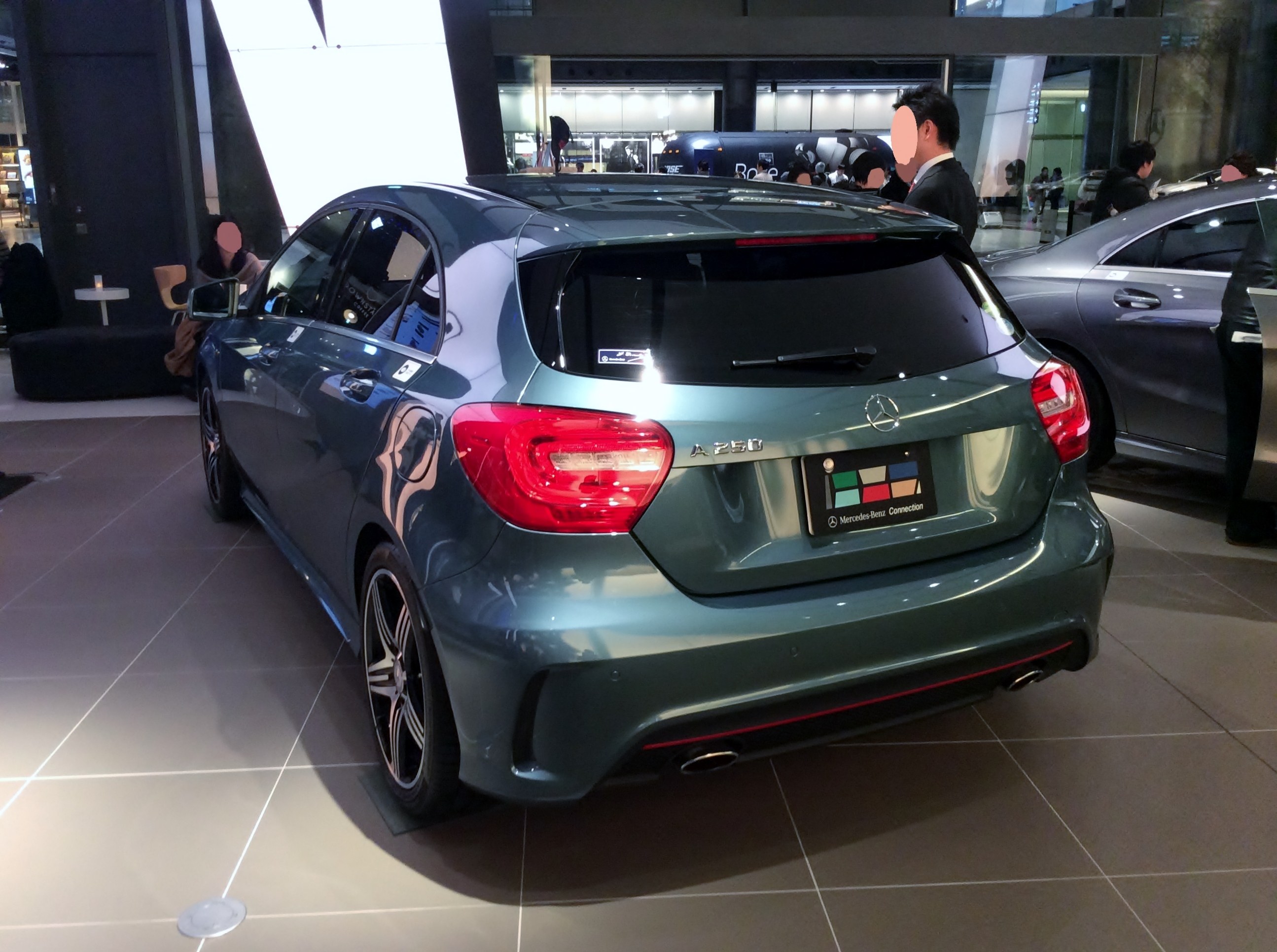 Ein Mercedes-Benz A-Klasse Hatchback auf der IAA in Frankfurt, ein schlankes, modernes Design mit glänzender schwarzer Lackierung und Chromakzenten, umgeben von einer Gruppe von Menschen.