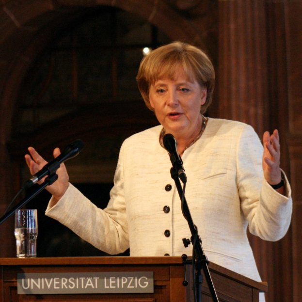 Bundeskanzlerin Angela Merkel bei einer Rede an einem Pult mit Mikrofon und einem Glas Wasser an der Universität Leipzig.
