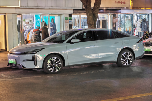 Ein Mitsubishi Lancer EV auf einer nächtlichen Straße geparkt, umgeben von Gebäuden, Geschäften, Schaufensterpuppen, Schildern und Lichtern.