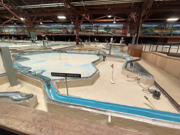 Indoor-Wasserpark mit mehreren Rutschen, Deckenleuchten, Wandgemälde und Minigolfplatz.