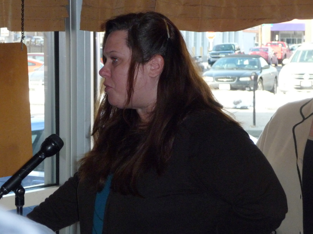 Eine Frau spricht mit einer anderen Person hinter ihr, mit einem Fenster, das mehrere Fahrzeuge zeigt.