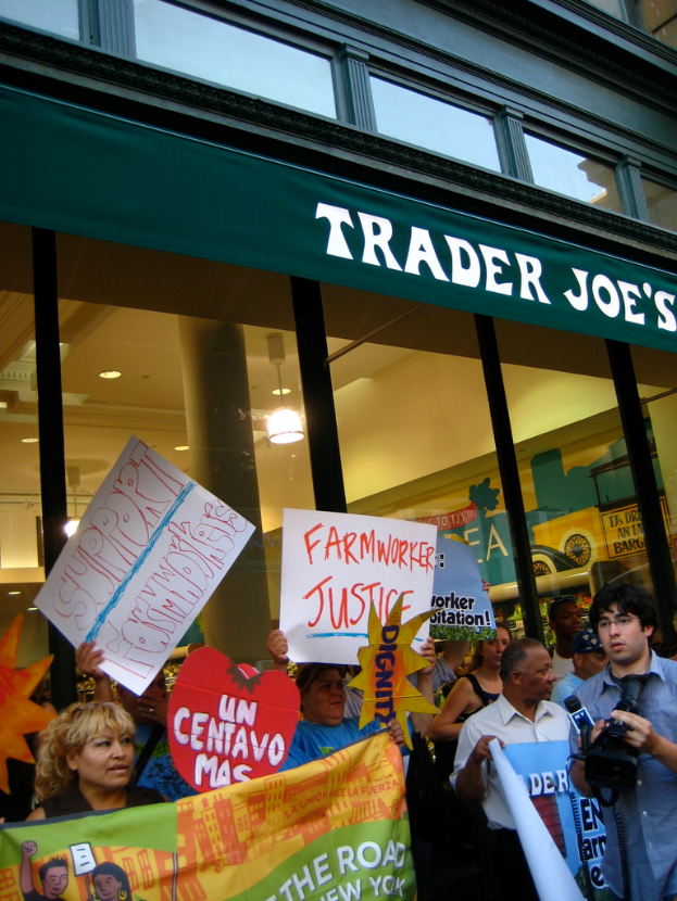 Eine Gruppe von Menschen steht in der Nähe eines Ladens und hält Schilder und Plakate.