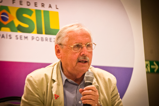 Eine Person, die in ein Mikrofon spricht und im Hintergrund ein Banner mit der Aufschrift 'bundesweit' zu sehen ist.