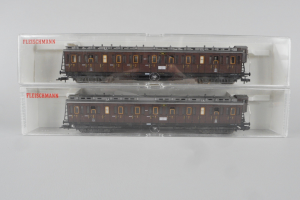 Zwei braune Modellzug-Gepäckwagen in einer klaren Box auf einem weißen Hintergrund.