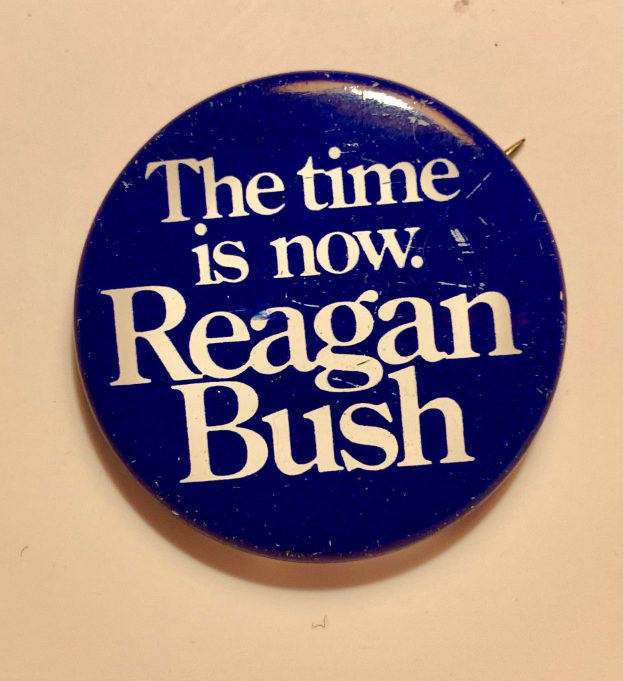 Ein blauer Ansteckknopf mit der Aufschrift "Die Zeit ist jetzt Reagan Bush".