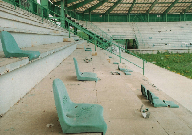 Ein Stadion mit verstreuten Stühlen, Grasboden und sichtbaren Treppen.