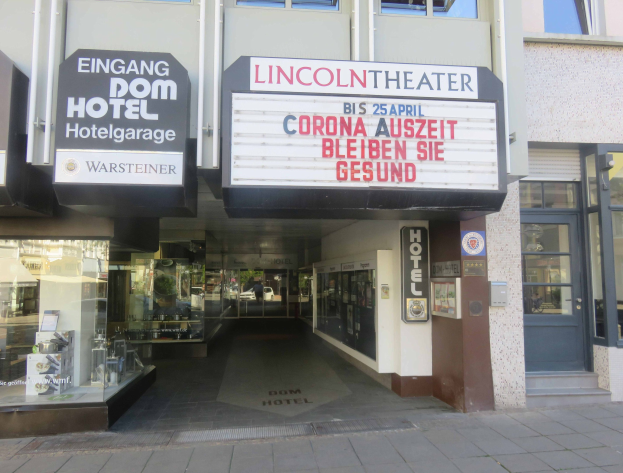 Außenansicht des Lincoln Theaters in Berlin, Deutschland, mit Glasfenstern und -türen und einer Tafel mit Text sowie einem belebten Innenraum