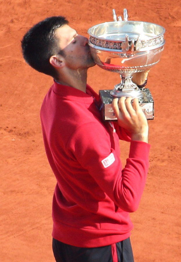 Novak Djokovic hält den French-Open-Pokal nach dem Sieg gegen Rafael Nadal im Finale der Herren-Einzel, feiert mit triumphaler Miene.