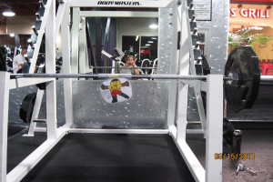 Ein Gymnastikraum mit einem Gewichtsständer im Vordergrund, einem Mann auf der linken Seite und einer Frau in der Mitte.