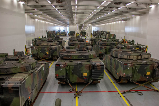 Ein grosser Militaraustellungsraum mit zahlreichen Tanks in einer ordentlichen Reihe unter Deckenleuchten.