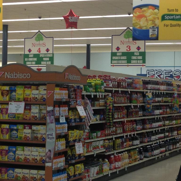 Ein Supermarktinneres mit sichtbaren Lebensmitteln, Deckenleuchten und Beschilderung.