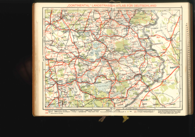 Ein altes Buch mit einer detaillierten Deutschlandkarte auf dem Cover, die Straßen und Autobahnen zeigt, vor einem schwarzen Hintergrund.