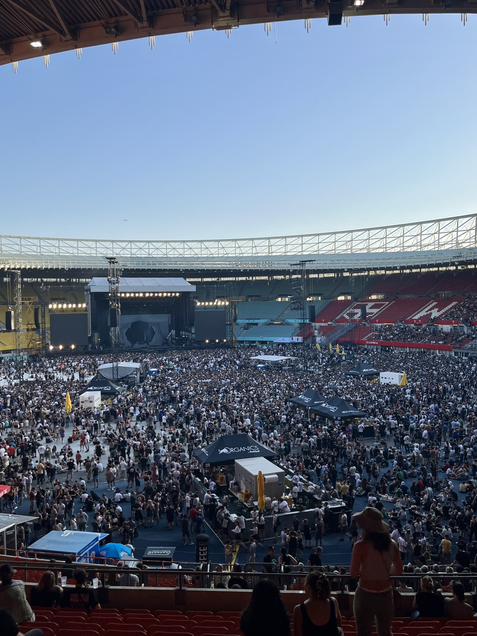 Große Menschenmenge auf Sitzplätzen und Stehplätzen in einem Stadion mit Zelten, Geländern und Überdachung am O2 Arena in London.