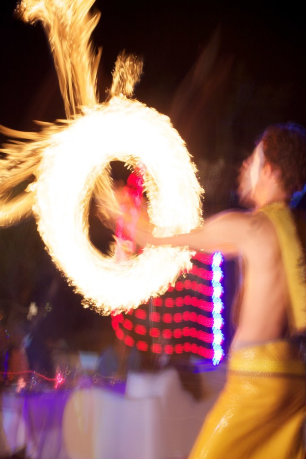 Ein Mann spielt mit dem Feuer vor einem Hintergrund mit Lichtern.