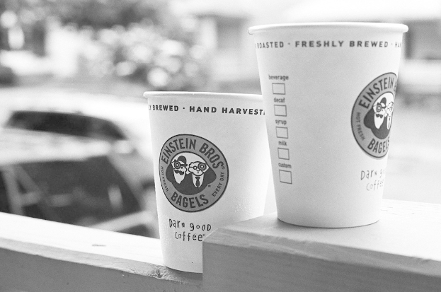 Zwei Tassen sind an einer Wand angebracht, mit einem Auto im Hintergrund.