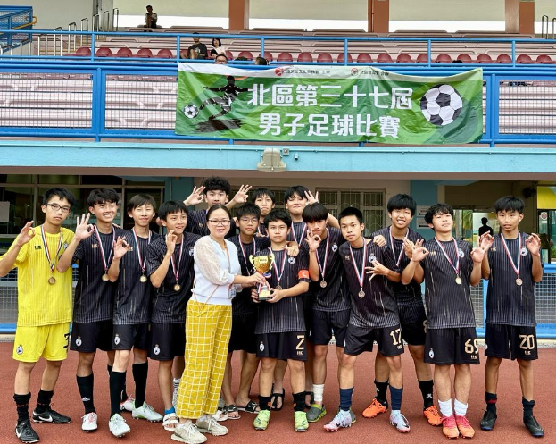 Gruppe junger Männer in Fußballtrikots auf einem Feld mit einem Pokal und einem 'Yokohama U-16 Jungen Fußballteam' Banner im Hintergrund.