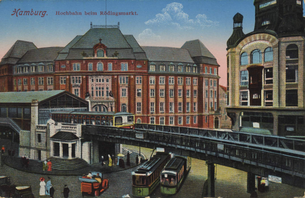 Ein altes Postkartenmotiv zeigt einen Bahnhof in Hamburg, Deutschland, mit Menschen, Fahrzeugen, Gebäuden, einer Brücke und einem bewölkten Himmel sowie Text oben.