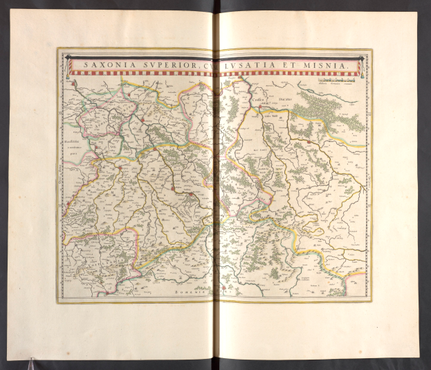 Ein aufgeschlagenes Buch mit einer detaillierten Karte von Sachsen, die die Provinzen und Städte hervorhebt, vor einem schwarzen Hintergrund.