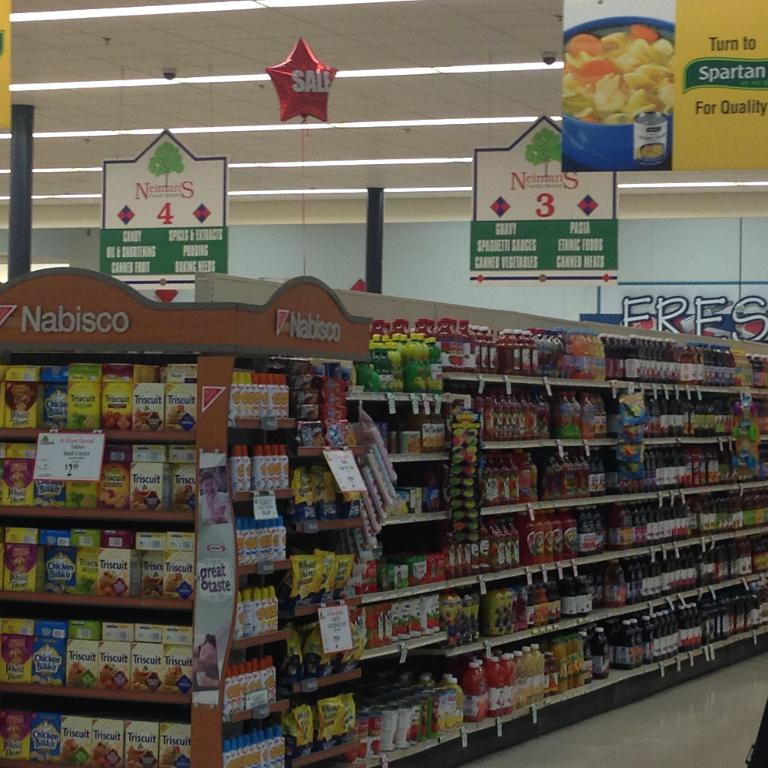 Ein Supermarktinneres mit Lebensmitteln, Deckenleuchten und Schildern.