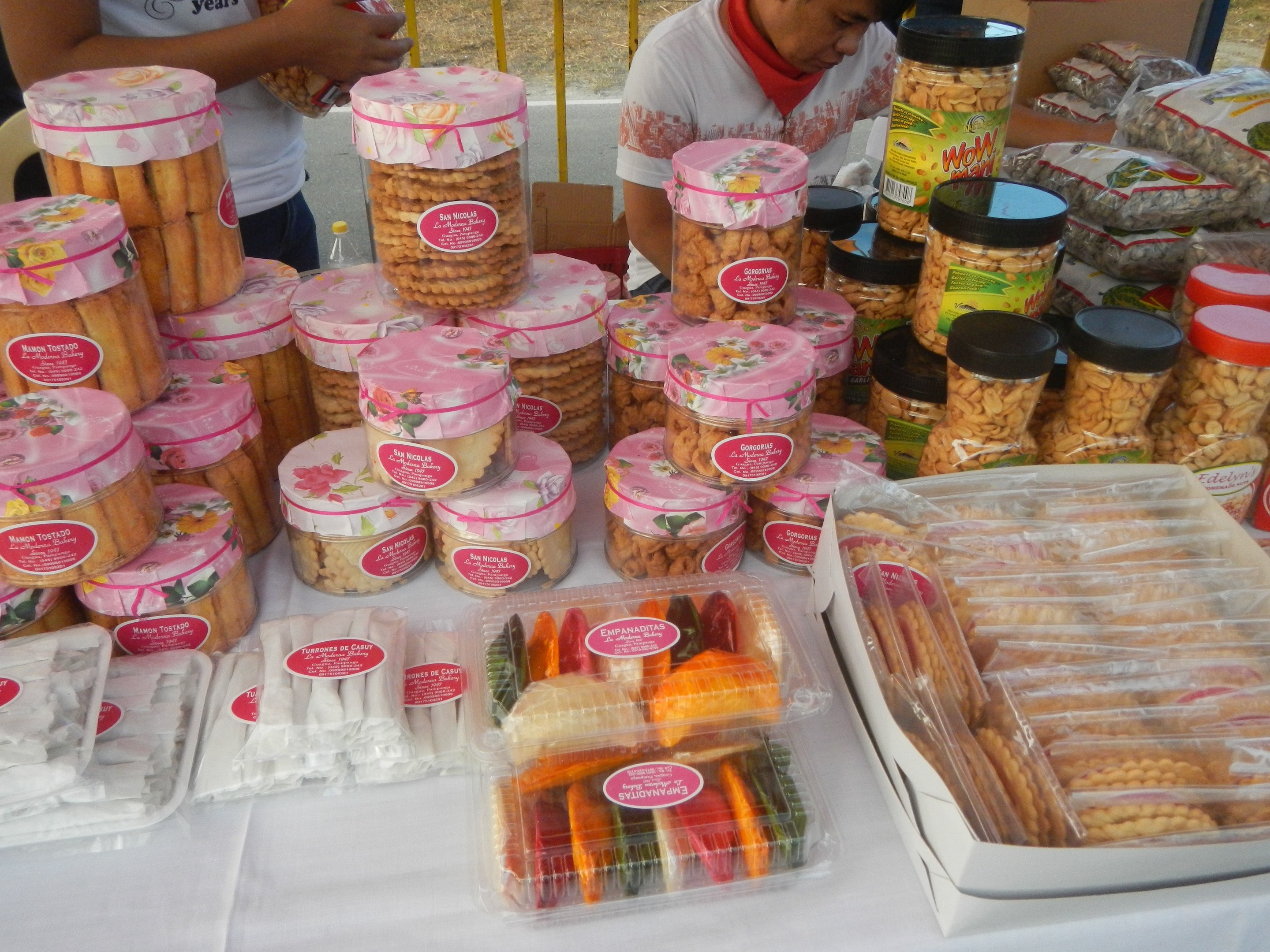 Eine Gruppe von Menschen umringt einen Tisch mit verschiedenen Speisen auf einem Outdoor-Festival.