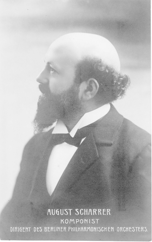 Ein Schwarz-Wei├č-Foto von August Scharrer, einem deutschen Komponisten, der einen Blazer und eine Fliege tr├Ągt, mit Text am unteren Bildrand.