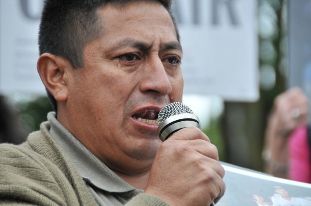 Eine Person in einer Jacke hält ein Mikrofon in der rechten Hand.