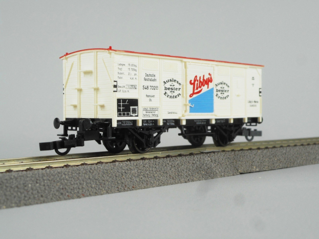 Ein rotes und wei├čes gestreiftes Spielzeugboxauto sitzt auf einer Schiene gegen einen wei├čen Hintergrund.