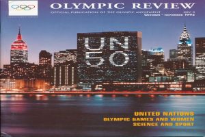 Ein Buch mit dem Titel "Olympic Review Official Publication of the Olympic Movement" mit einer Stadtansicht auf dem Cover, die Gebäude, Lichter und Wasser zeigt, auf einer flachen Oberfläche.