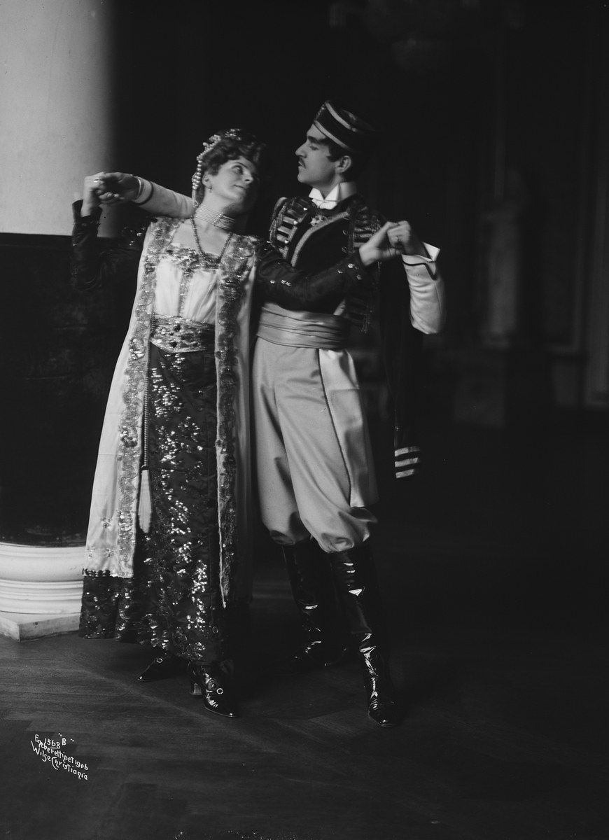 Schwarz-weiß-Foto eines Mannes und einer Frau, die in einem Ballsaal tanzen, mit einer Säule und einer Wand im Hintergrund; der Mann trägt Schuhe, was darauf hinweist, dass sie eine Vorstellung geben.