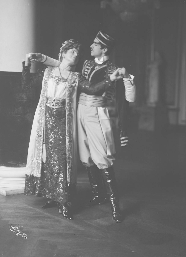 Schwarz-weiß-Foto eines Mannes und einer Frau, die in einem Ballsaal tanzen, mit einer Säule und einer Wand im Hintergrund; der Mann trägt Schuhe, was darauf hinweist, dass sie eine Vorstellung geben.