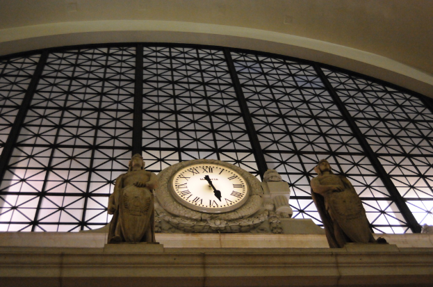 Ein Gebäude mit einer Uhr daran und einer Skulptur in der Nähe.
