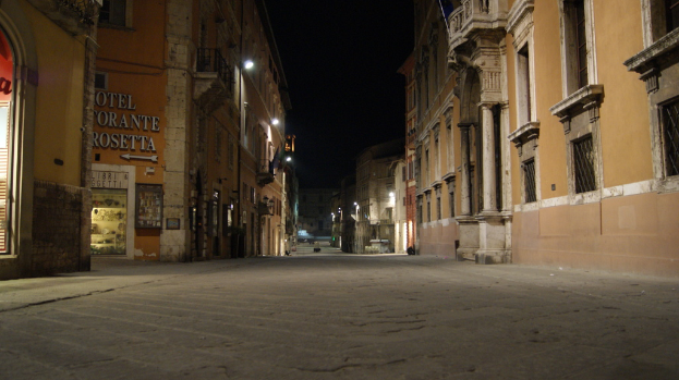 Eine nächtliche Straßenansicht mit Gebäuden auf beiden Seiten, einem Geschäft auf der linken Seite und Lichtern in der Mitte.