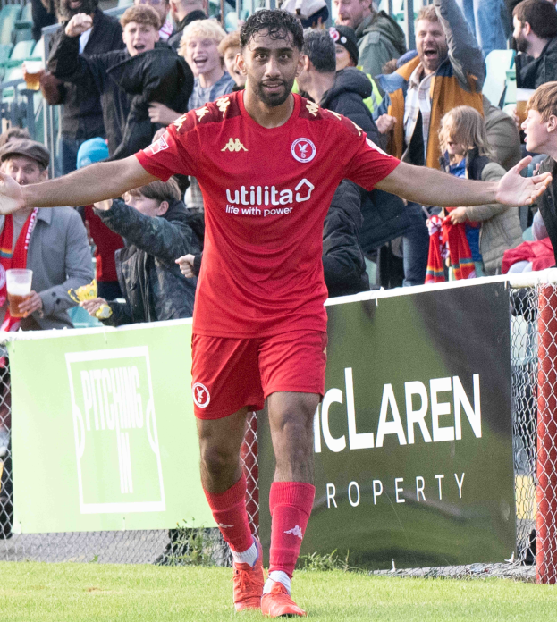 Fußballspieler in roter Uniform rennt mit ausgebreiteten Armen auf einem Feld, im Hintergrund eine Menschenmenge und im Vordergrund ein Banner mit der Aufschrift "Middlesbrough FC v Swansea City - Sky Bet Championship"