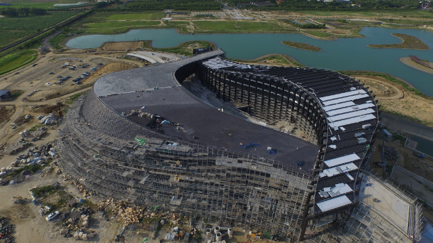 Ein Gebäude, ein Gewässer und ein Auto auf einer grünen Fläche.