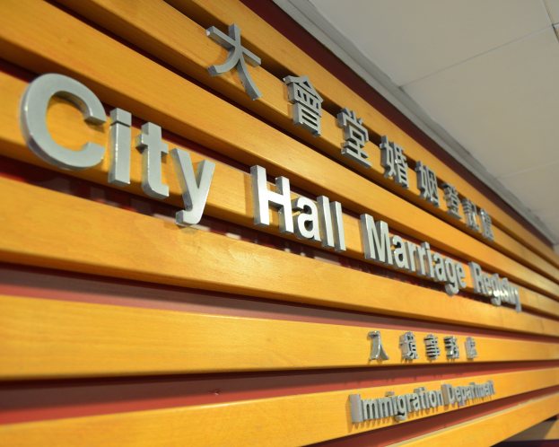 Holzschild mit der Aufschrift 'Standesamt' an der Seite eines Gebäudes unter einer Decke angebracht.