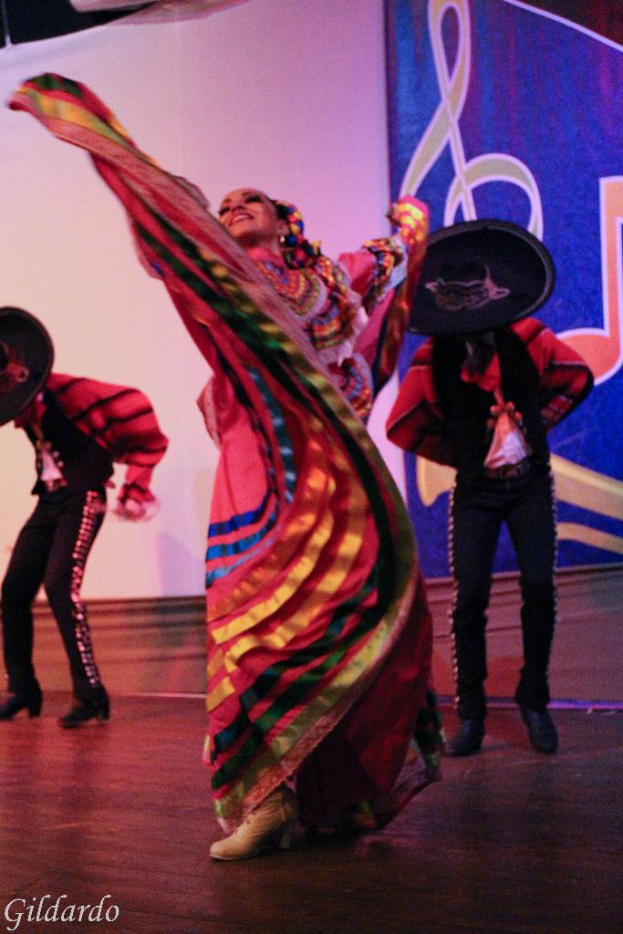 Leute stehen auf einer Bühne in Kostümen, mit einem Vorhang mit einem Bild im Hintergrund.