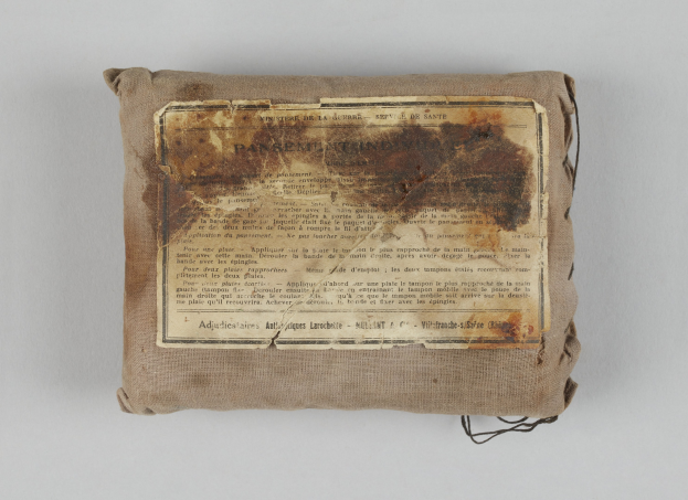 Kleiner Verbandskasten mit einem informativen Blatt oben drauf.