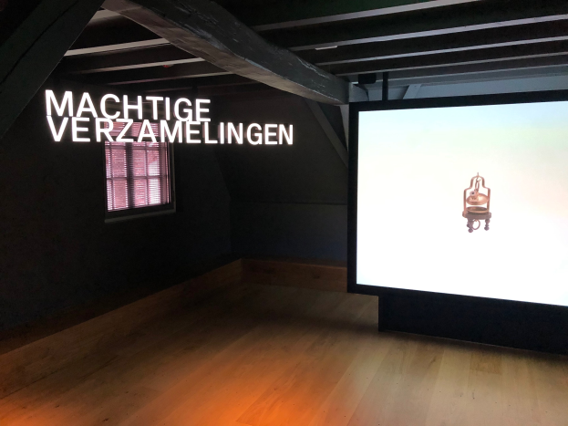 Installationsansicht der Ausstellung 'Machtige Sammlung' im Museum of Modern Art in Berlin, mit einem großen Bildschirm auf der rechten Seite und einem Fenster auf der linken Seite.