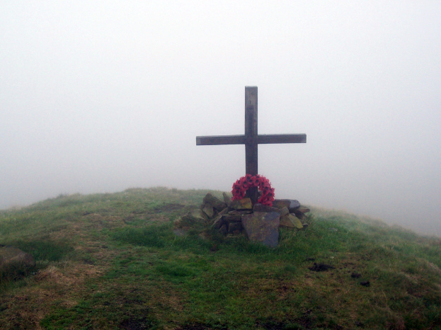 Ein Grab mit einer pinken Girlande vor einem Kreuz umgeben von Schnee.